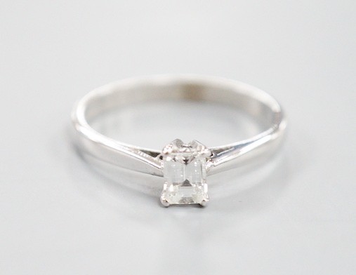 A modern 18ct white metal and solitaire emerald cut diamond set ring, size K, gross weight 2 grams